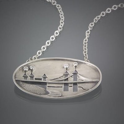 A commissioned silver pendant featuring a bridge image.