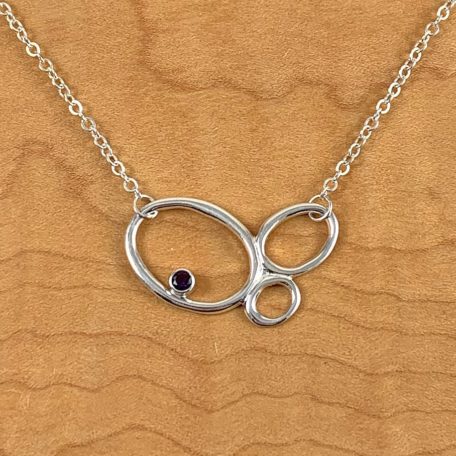 An Ebb Tide Necklace with a garnet stone.
