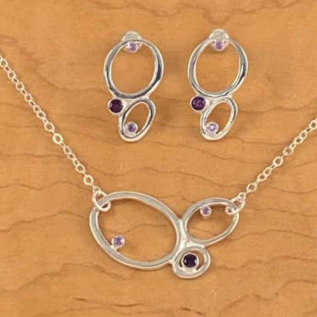 A set of silver Sandpiper Earrings paired with a purple amethyst necklace.